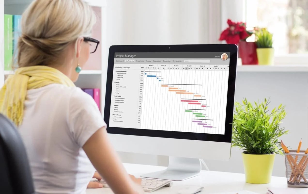 woman working at a desk looking at project management software