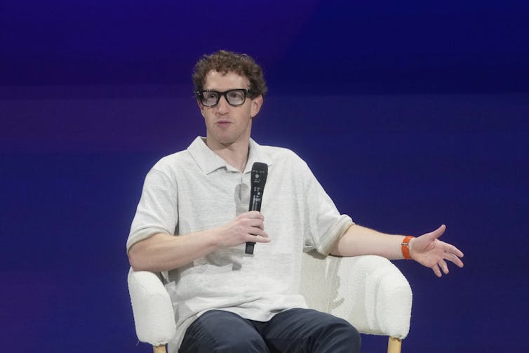Photo of Mark Zuckerberg sitting on a stage holding a microphone.