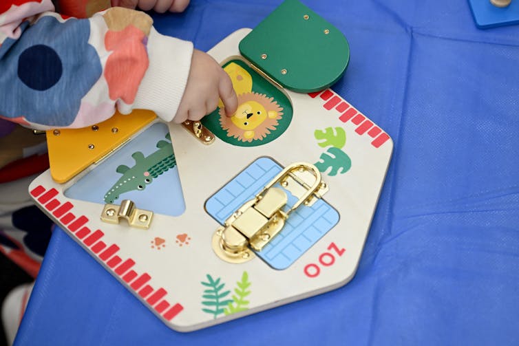 A young child plays with a wooden toy.