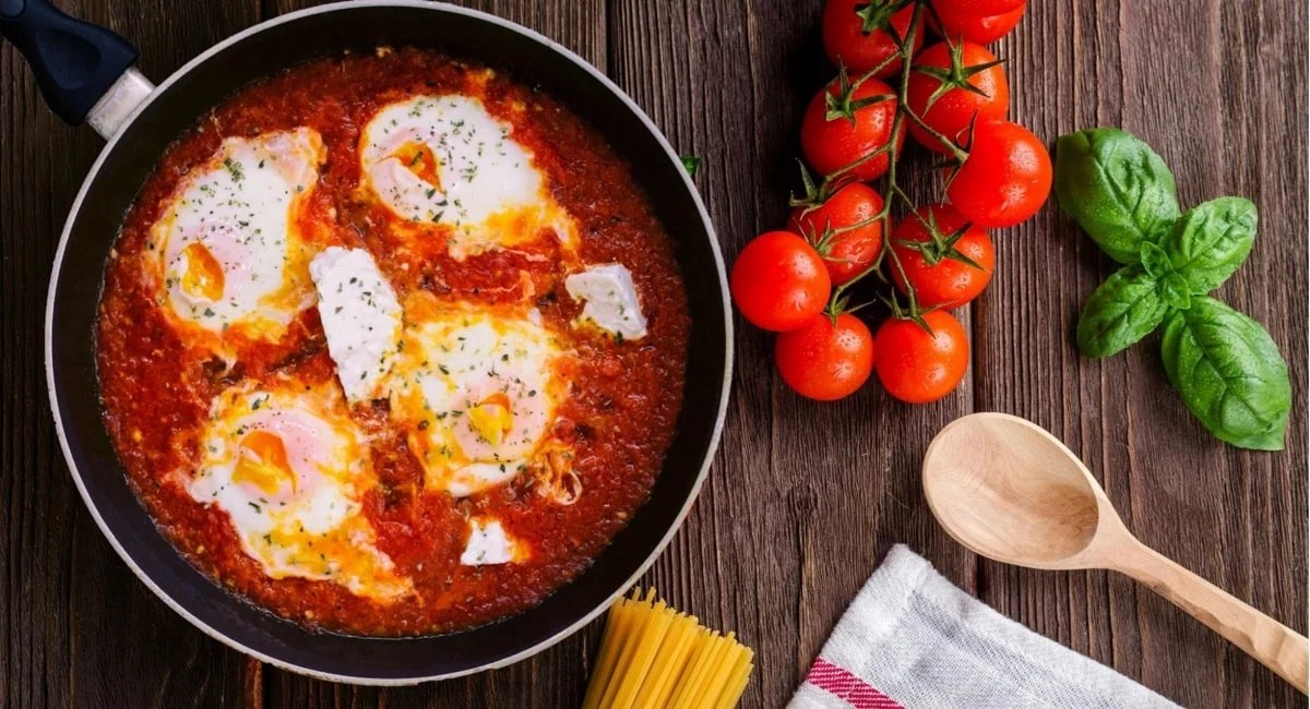egg and tomato dish in a skillet, next to ingredients