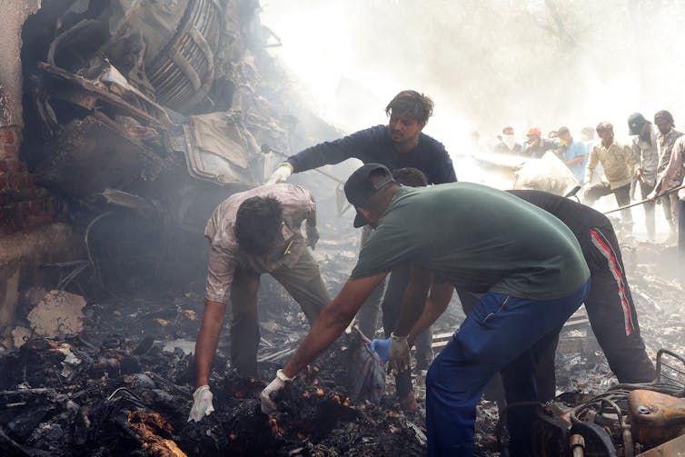 Men picking up wreckage at a crash site.
