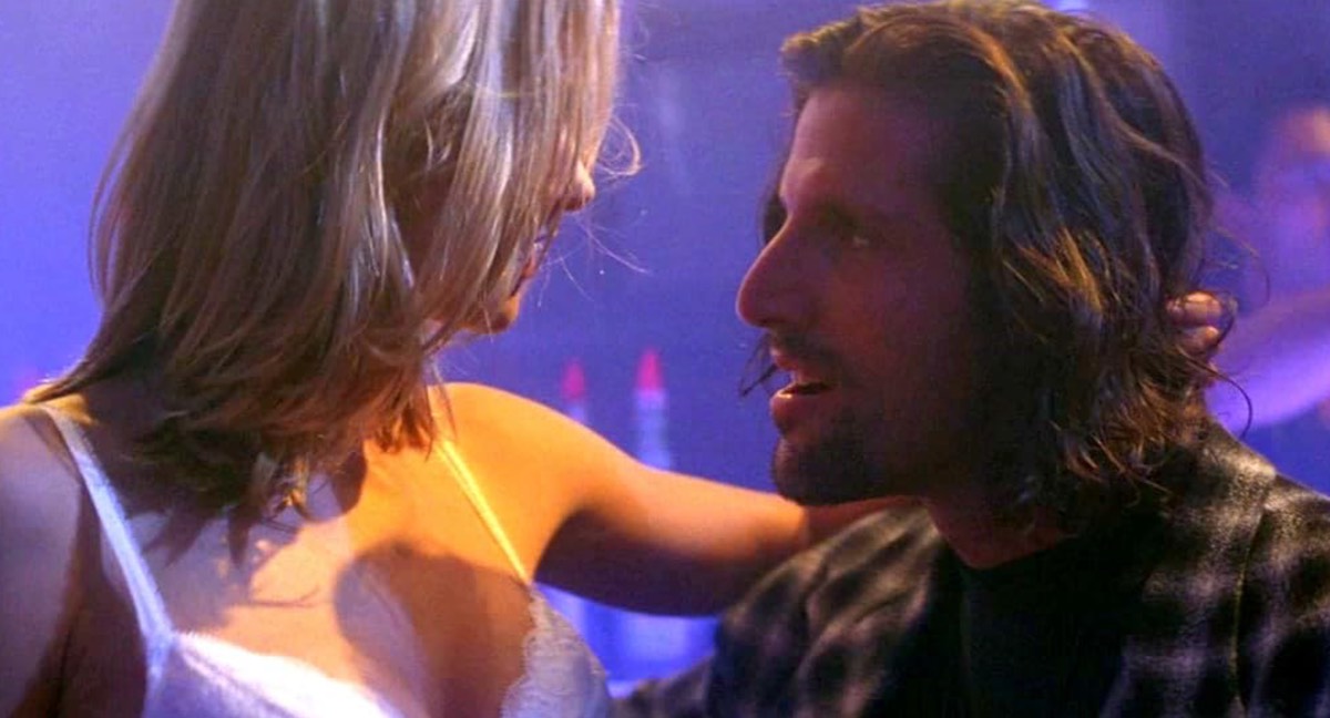 blonde woman in a bra embracing a man in a goatee