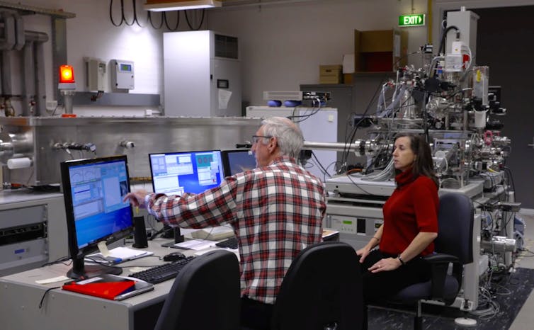 Two people sitting in front of computer screens in a laboratory.