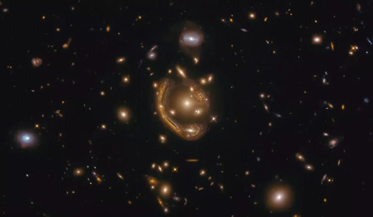 A foreground cluster of galaxies is warping a galaxy in the background, causing it to appear elongated and distorted. Due to the magnification we can see the galaxy in impressive detail.