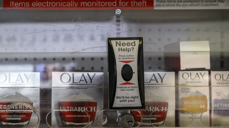 Face creams inside a locked display cabinet at a Duane Reade pharmacy in New York, August 2023 – with a button to call for staff assistance.