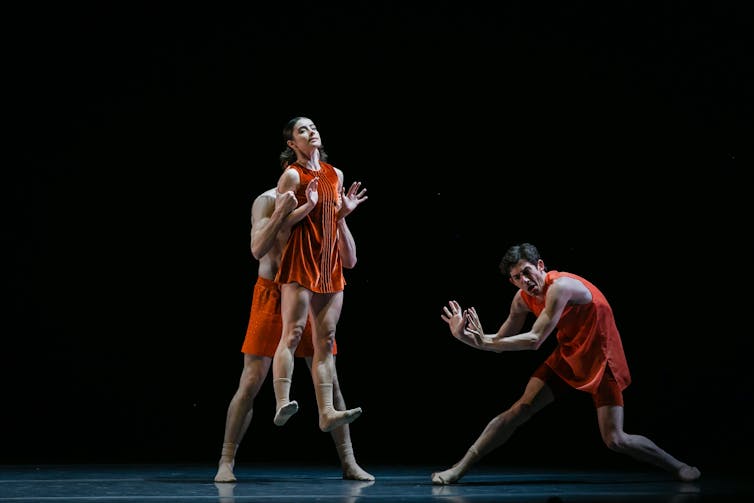Dancers on stage in orange costumes.