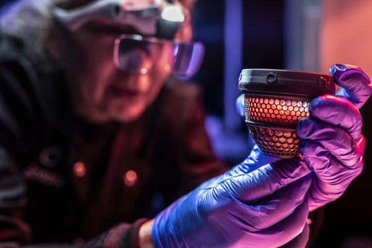 A person wearing safety glasses looking at a half-shell artificial egg.