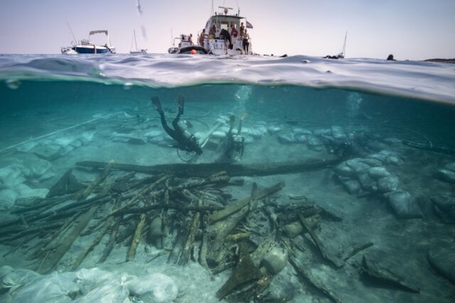 View of the excavation of the bow area of the Ilovik-Paržine 1 shipwreck. In the foreground, the cargo of logs and amphoras can be seen. Archaeologists are working near the structure of the bow complex.