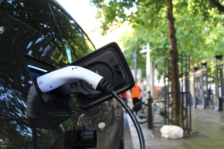 An electric vehicle charging in a street.