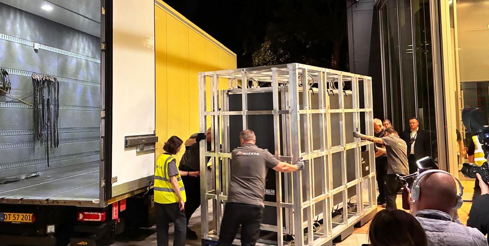 The tapestry arring in a crate being loaded from a yellow van in the middle of the night