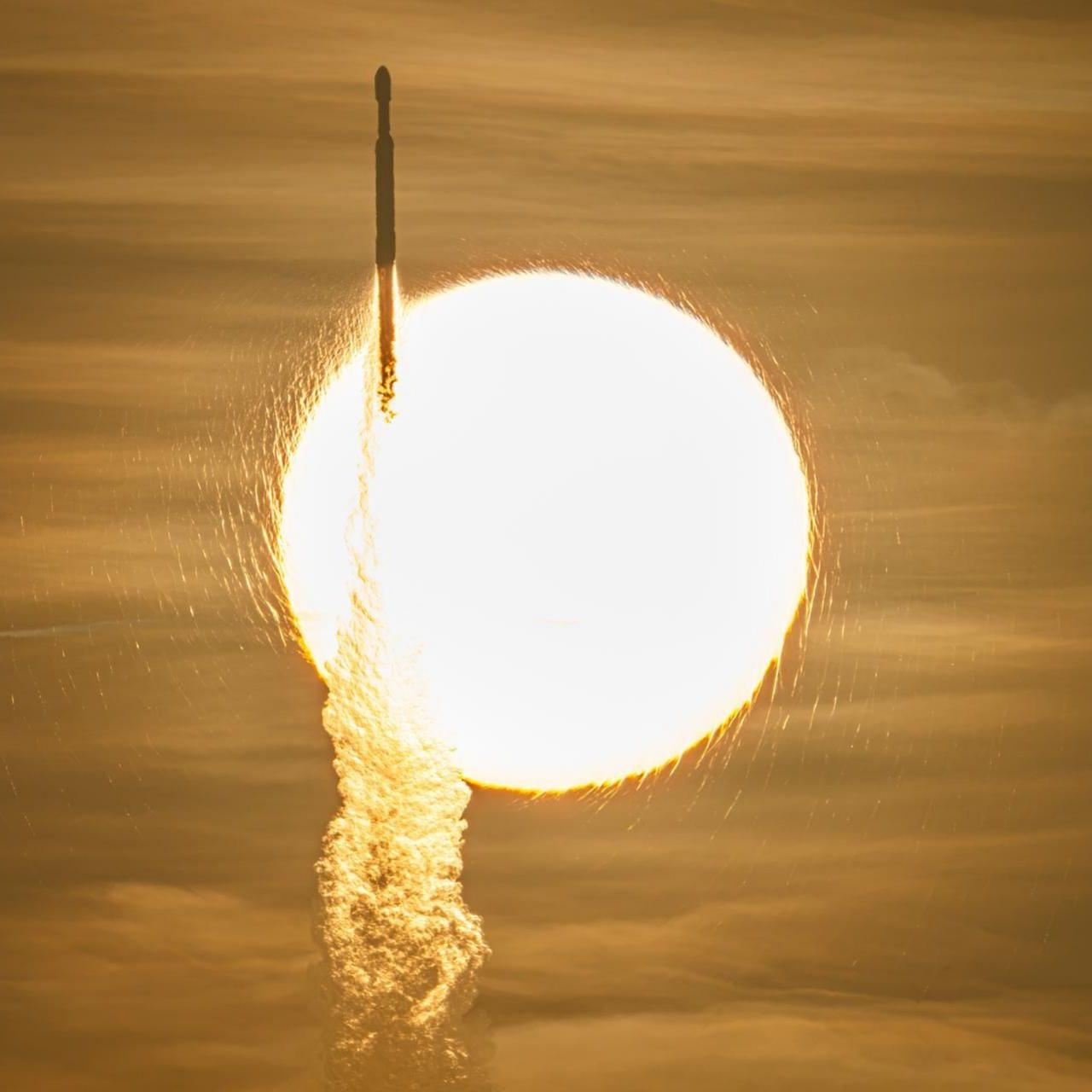 A view of a rocket launching off to space in front of the blaring yellow sun and yellow-tinted sky