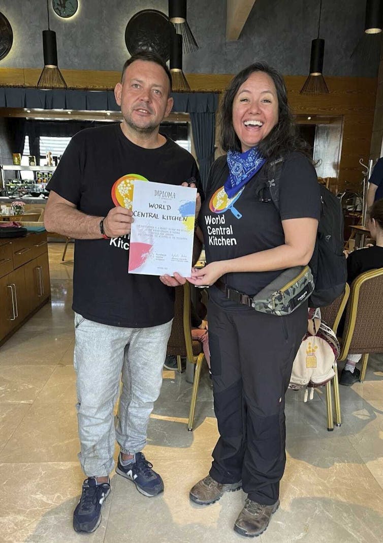 A man and a woman stand side by side, holding a certificate and smiling