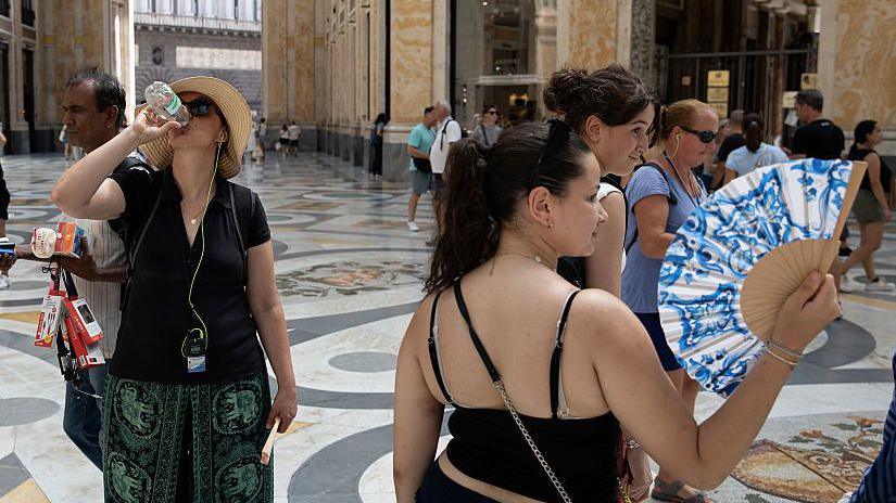 People drink water and use hand fans to protect themselves from the sun in Naples, southern Italy. Photo: 1 August 2026