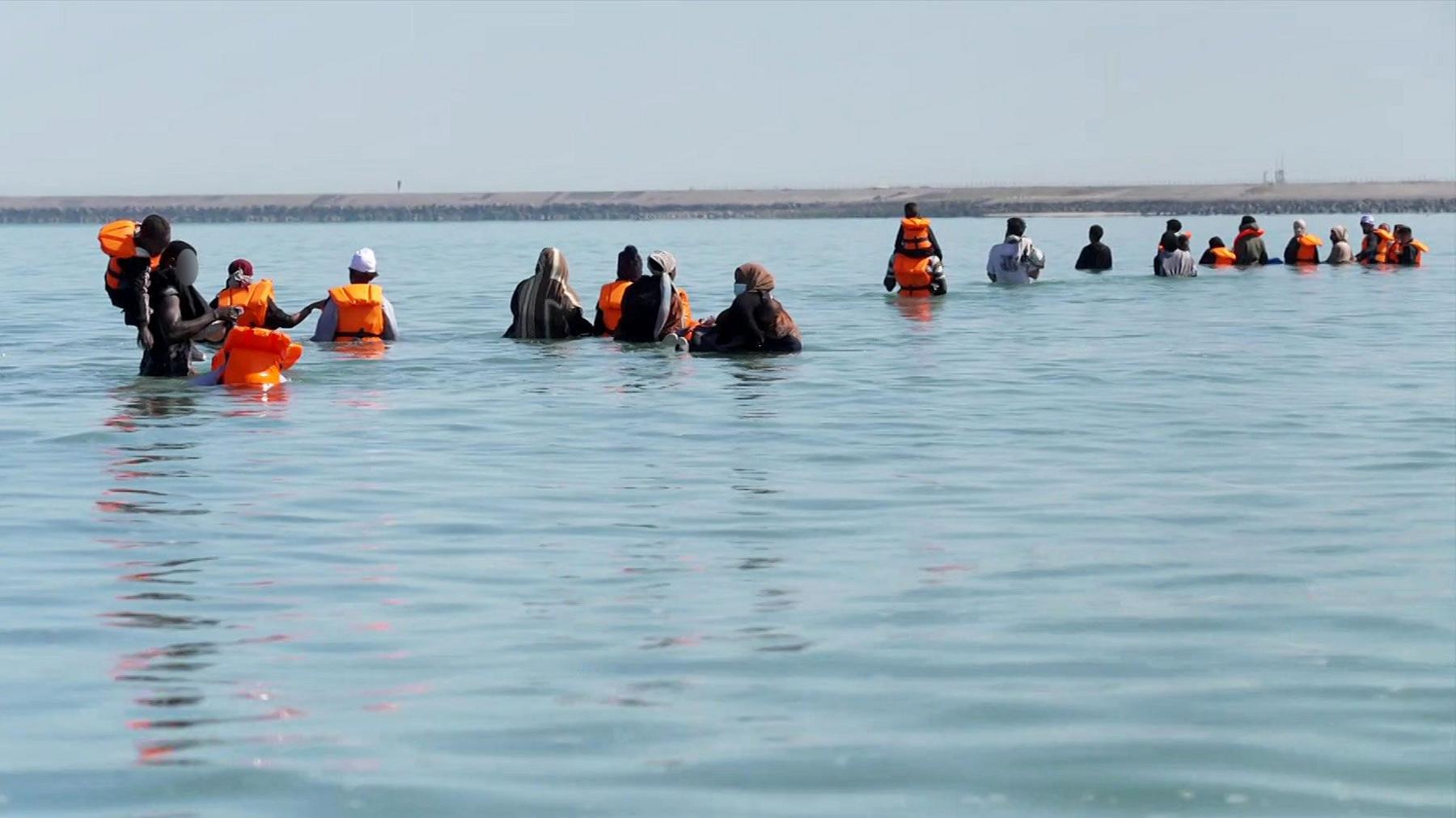A group of migrants wade through seawater on the beach in Gravelines, in a grab from the BBC video.