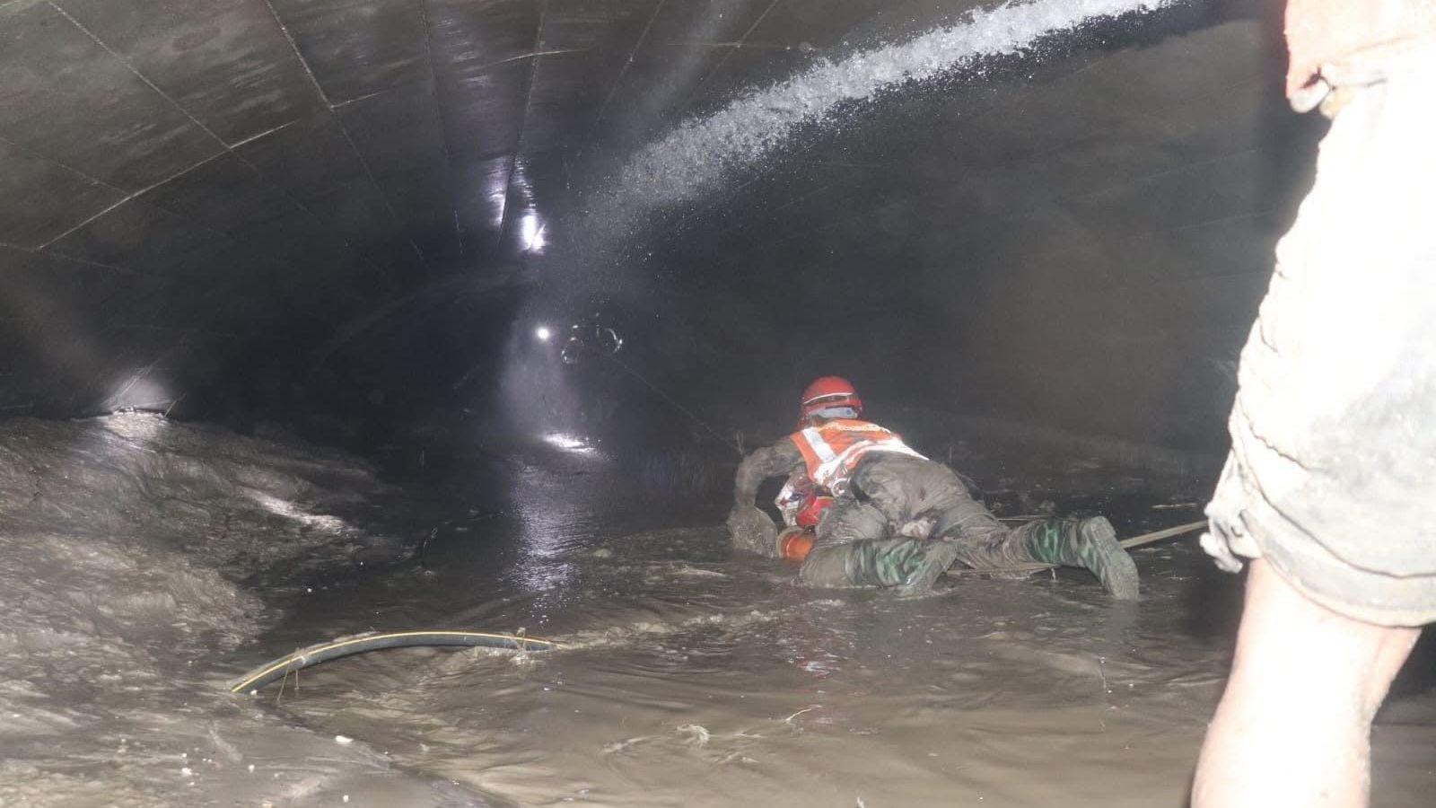 Nepalese rescuers wading through puddles of water in the Trishuli 3A tunnel