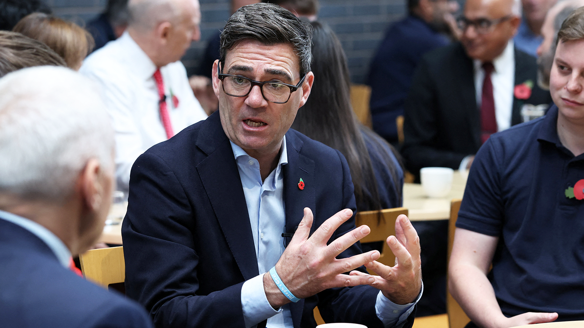 Andy Burnham sitting at an event in Derby with Chancellor John Healey in the background