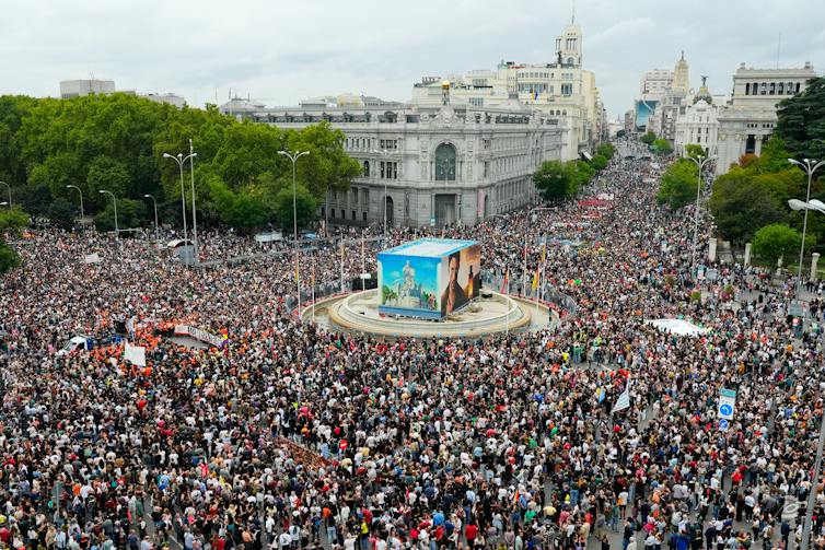 A large, European public square overflowing with protest crowds