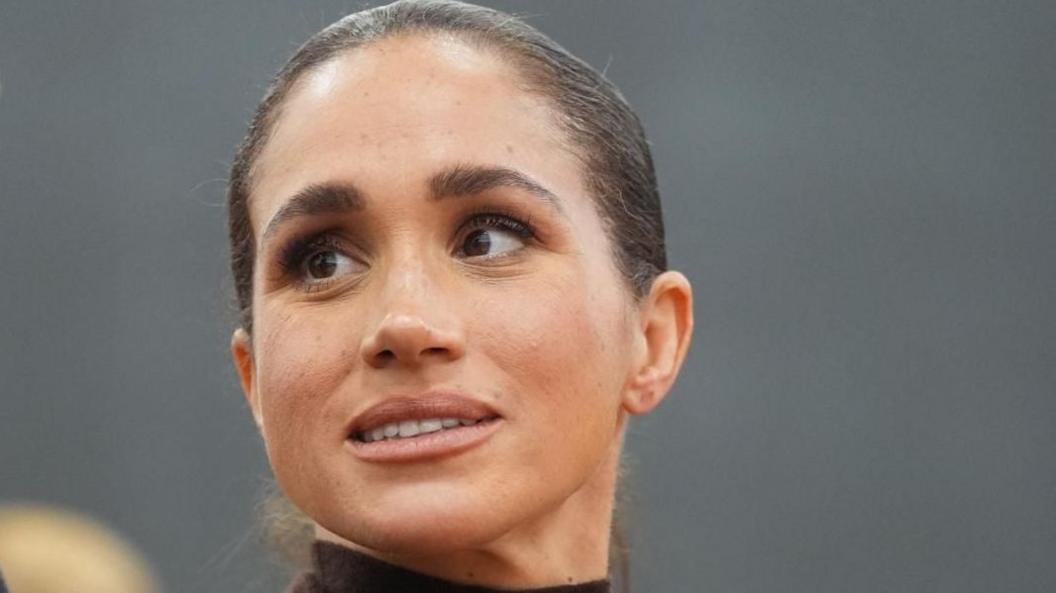 Head shot of the Duchess of Sussex in 2026. Her hair is pulled back and she is looking slightly to her right